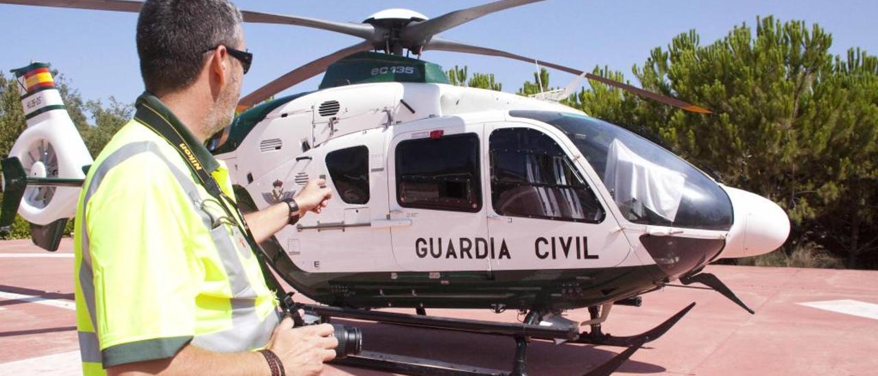 Un efectivo de la Guardia Civil junto a un helicóptero en una imagen de archivo.