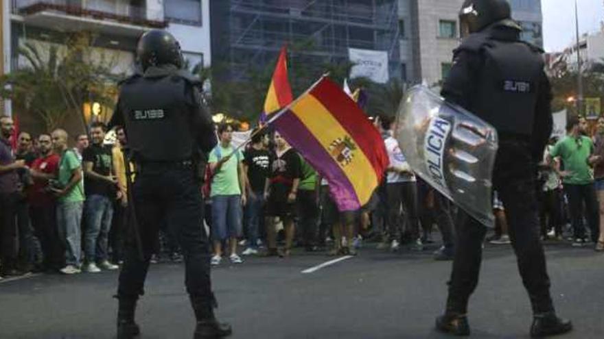 Una mujer preocupada por el futuro educativo de sus nietos. Arriba, un irónico mensaje de protesta. Abajo, los agentes antidisturbios en un momento de tensión.