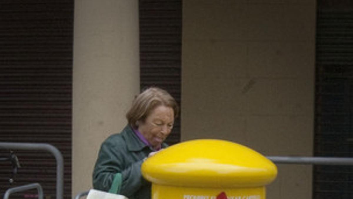 Una mujer trata de enviar una carta en un buzón de Correos tuneado con la bandera independentista.