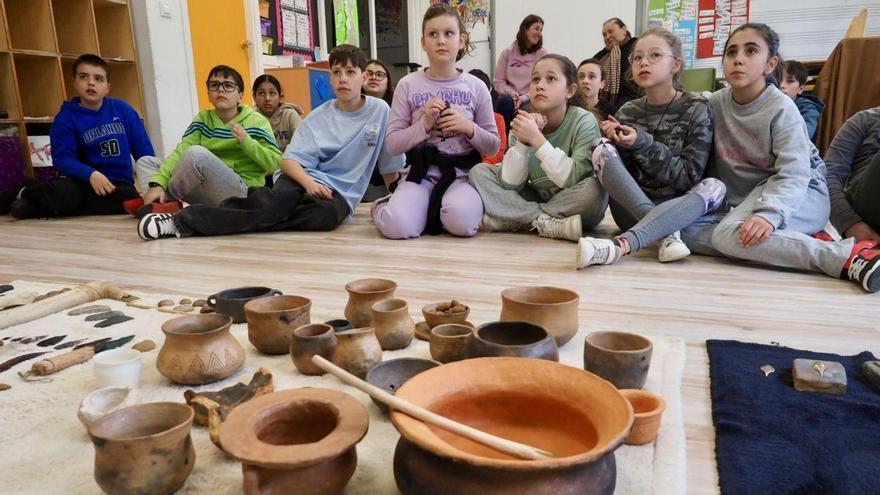 Los alumnos atienden delante de unas reproducciones de elementos prehistóricos. | Bernabé