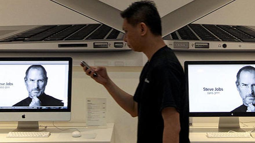Un hombre camina frente a unas pantallas con la imagen de Steve Jobs en en Singapur el pasado jueves.