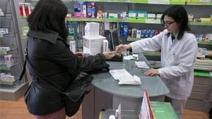 Una usuaria abona el euro por receta en una farmacia de Barcelona.