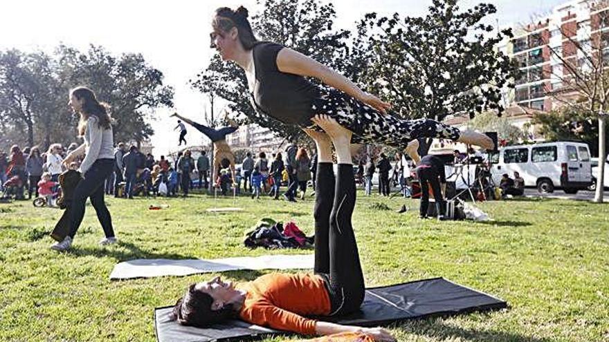 Acroioga en primer pla, equilibris en segon pla, i «slackline» al fons al parc Central.