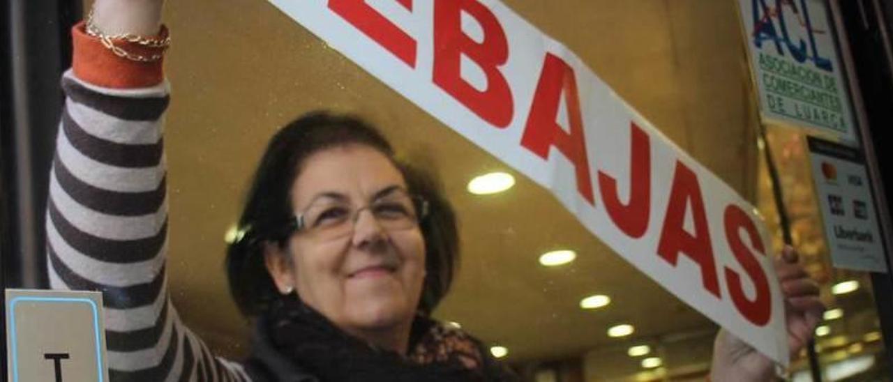 Olimpia García, en la puerta de su negocio de Luarca, anunciando las rebajas.