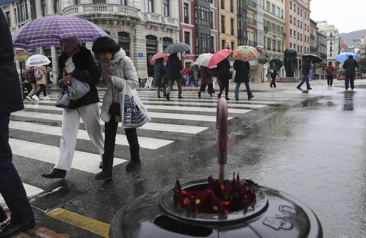 Paseantes en Oviedo con paraguas y abrigo