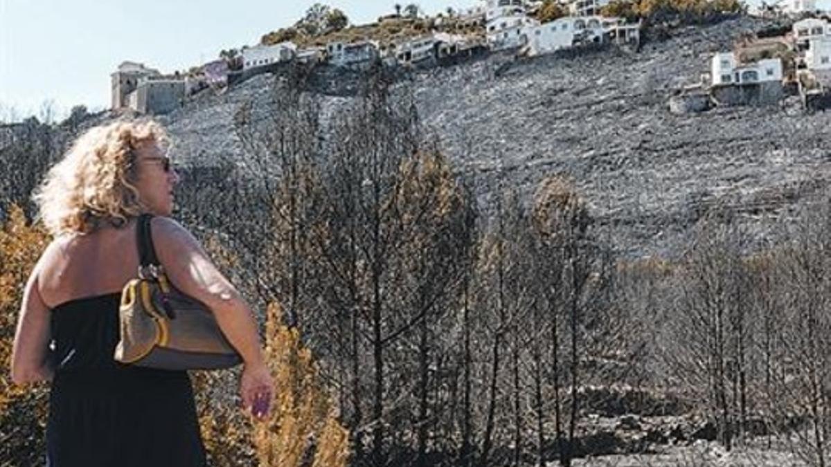 Una mujer observa unas viviendas afectadas por el fuego en Dénia, ayer.