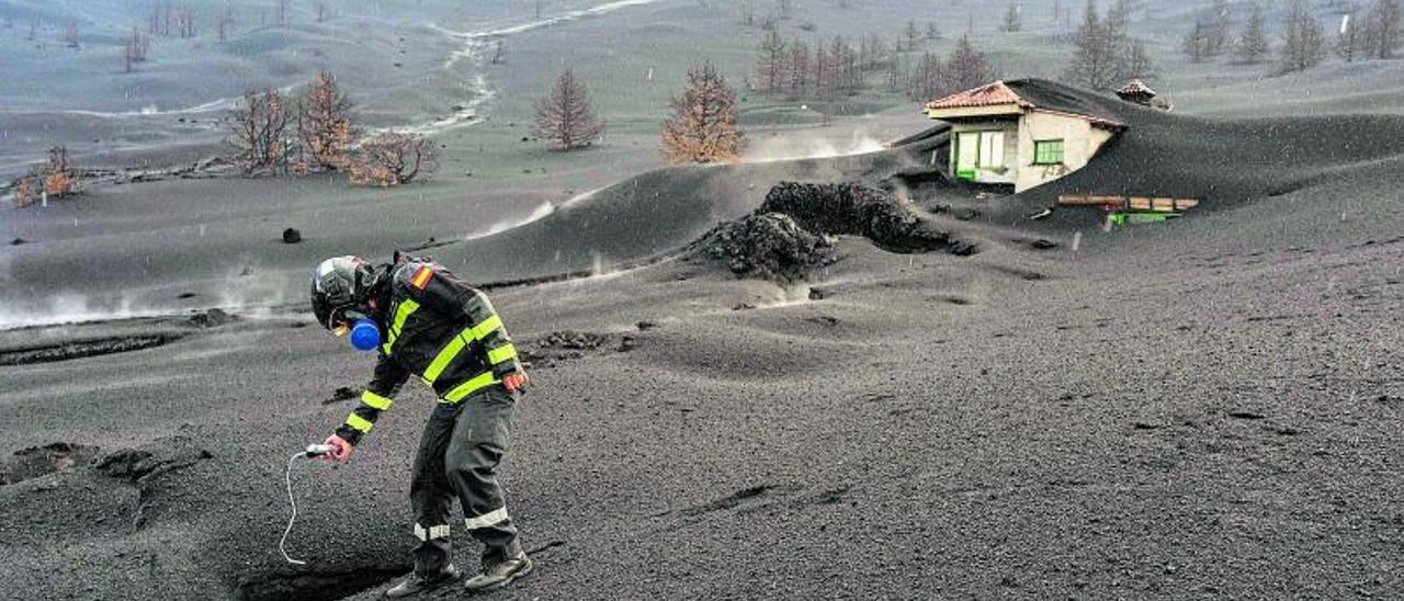 Un efectivo de la Unidad Militar de Emergencias (UME) mide los gases que emanan del volcán en la zona de exclusión .