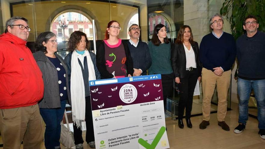Representantes de los seis grupos municipales y de Oxfam Intermón, con el cartel de la iniciativa.