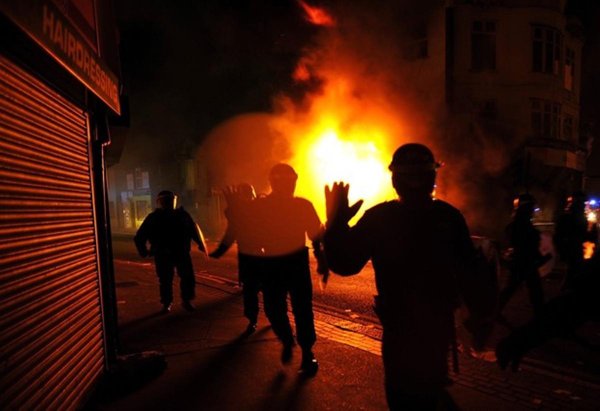 Agents de la policia realitzen una càrrega entre els edificis incendiats durant la protesta al sud de Londres (Anglaterra). Agents de la policia realitzen una càrrega entre els edificis incendiats durant la protesta al sud de Londres (Anglaterra).