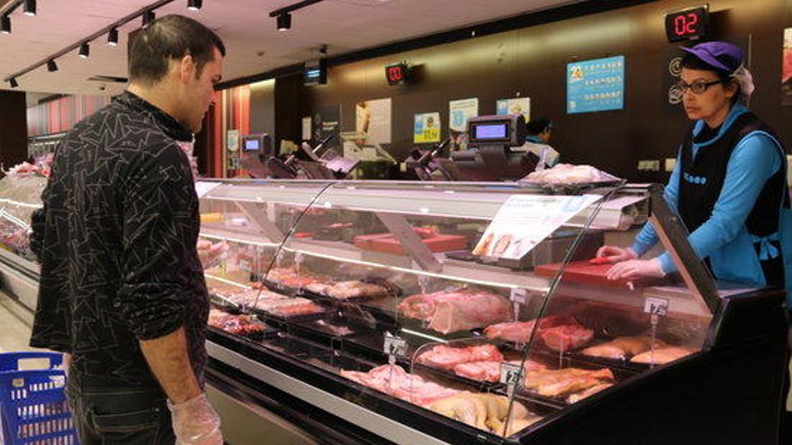 Un client amb guants comprant carn en un supermercat de l&#039;Espai Gironès.