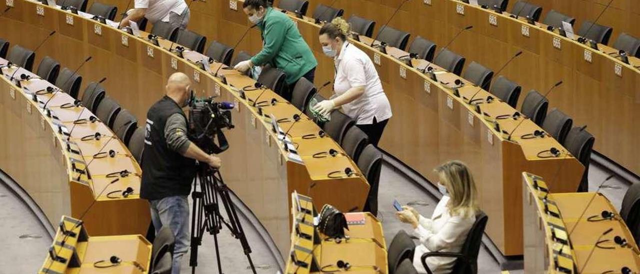 Limpiadores del Parlamento Europeo, desinfectando los escaños antes del arranque de la sesión plenaria. // Efe