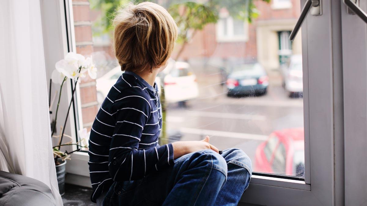 Un niño mira por una ventana.