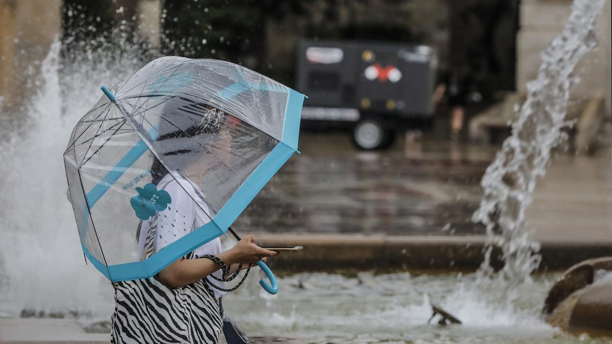 Una mujer pasea bajo un paraguas.