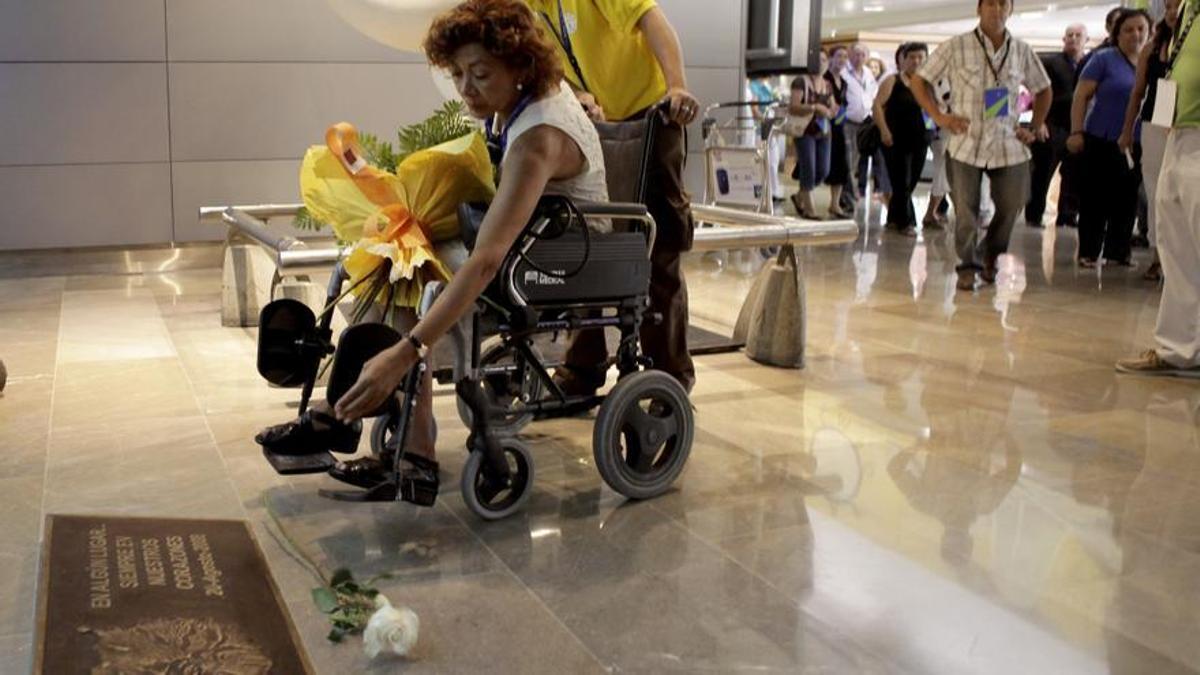 Loreto González, superviviente de la catástrofe, coloca unas flores en la placa conmemorativa de Barajas. Ella perdió a su única hija en el accidente.