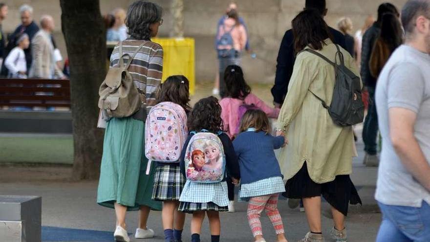 Unas madres con sus hijas acuden al primer día de colegio.