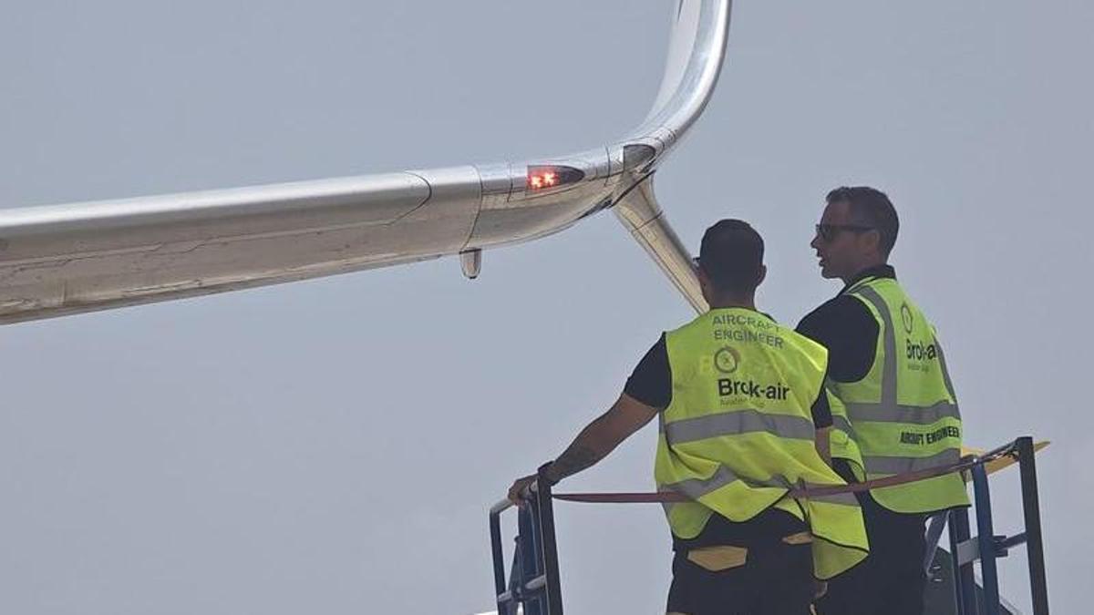 Varios operarios trabajan en la reparación del ala de un avión de Ryanair tras el impacto de una escalera