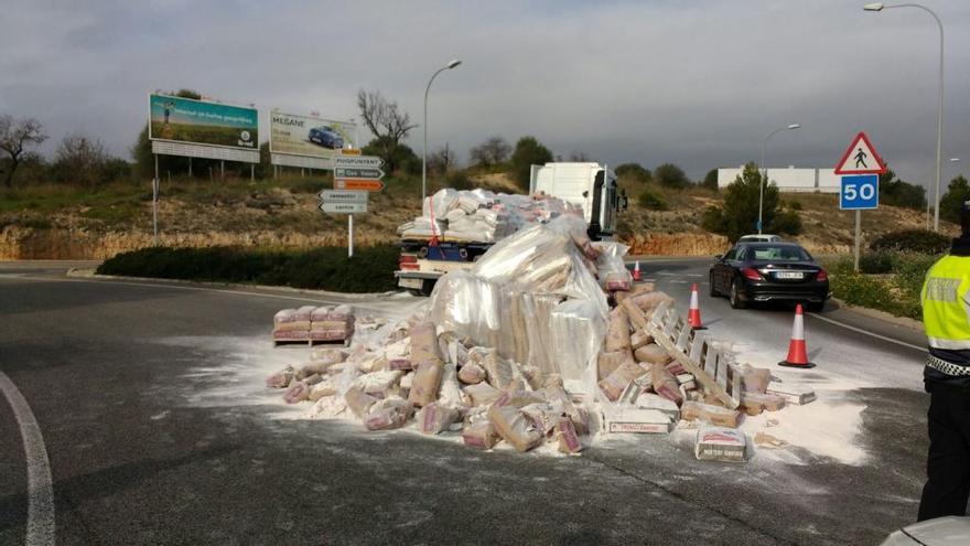 Un policía, junto a los sacos de cemento que ha perdido el camión