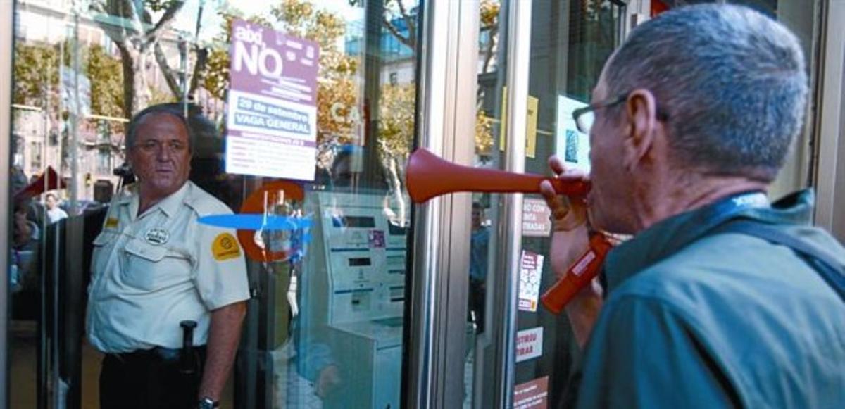 Un membre d’un piquet exigeix el tancament d’un banc al passeig de Gràcia davant la mirada d’un vigilant, ahir.