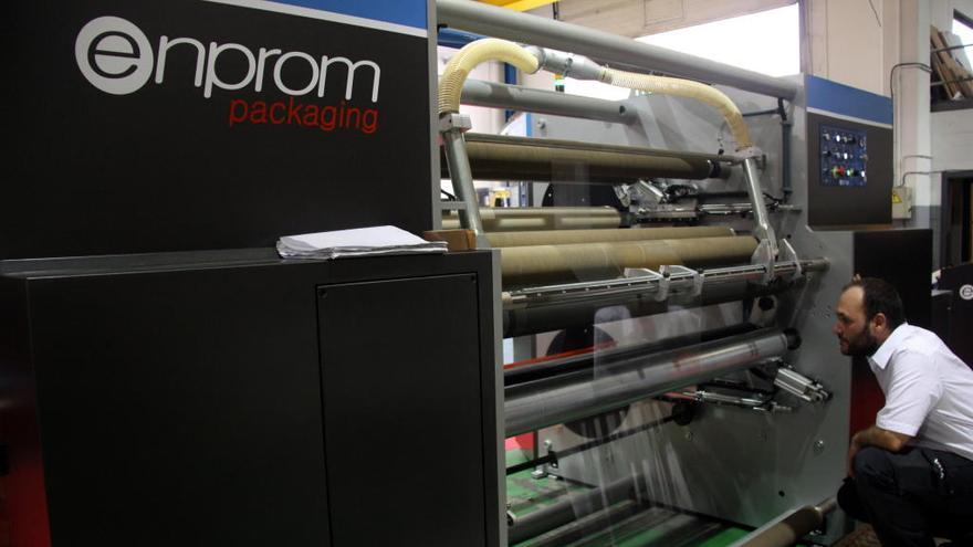 Un operari, al costat d&#039;una de les màquines per a etiquetatge que ha desenvolupat l&#039;empresa gironina Enprom
