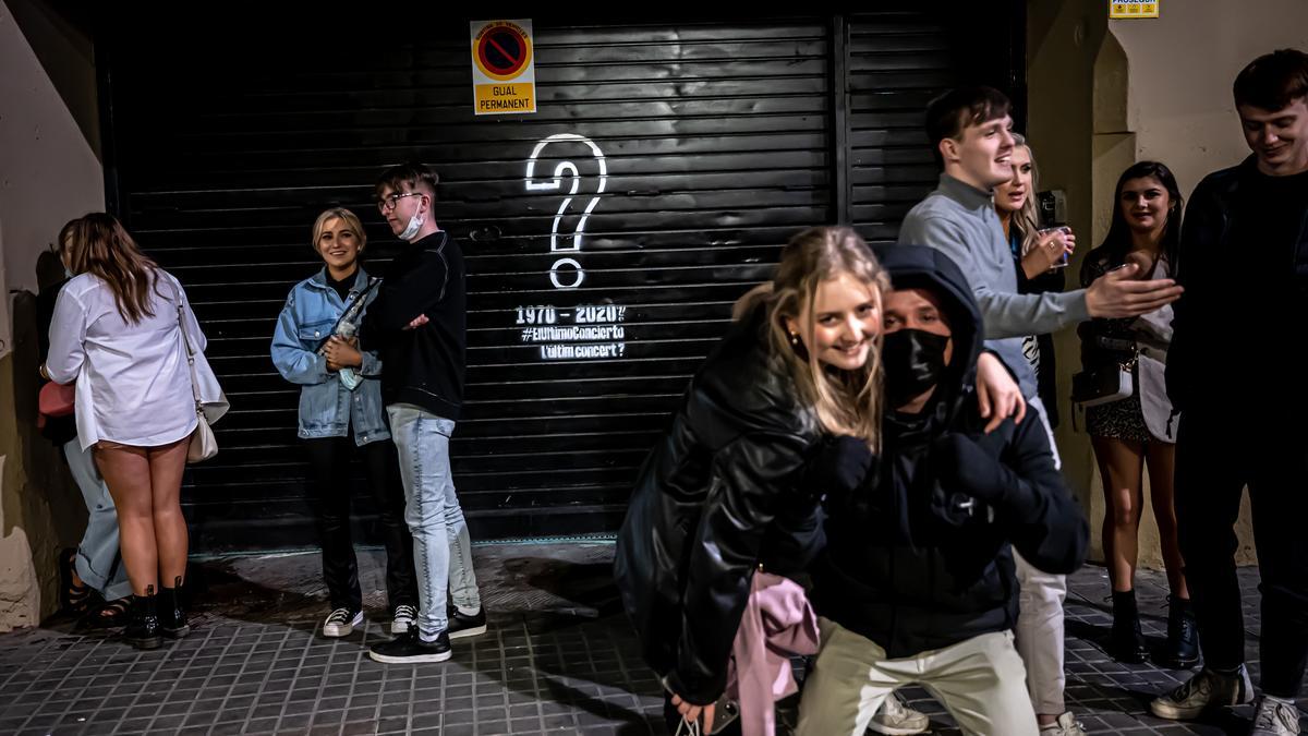 Ambiente tras el cierre de los locales de la plaza Reial de Barcelona. Jóvenes extranjeros beben frente a una discoteca con la persiana bajada
