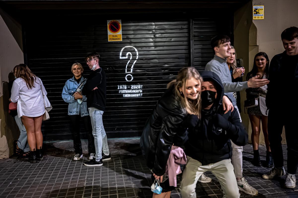 Ambiente tras el cierre de los locales de la plaza Reial de Barcelona. Jóvenes extranjeros beben frente a una discoteca con la persiana bajada.