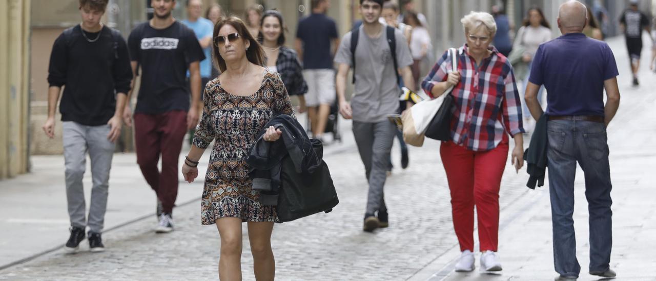 Gent passejant per Girona sense jaqueta i amb màniga curta.