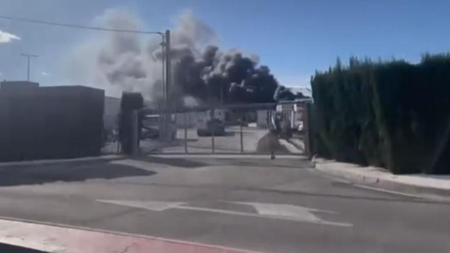 Imagen del acceso con la humareda provocada por el incendio del desguace en el que se acumulan miles de vehículos