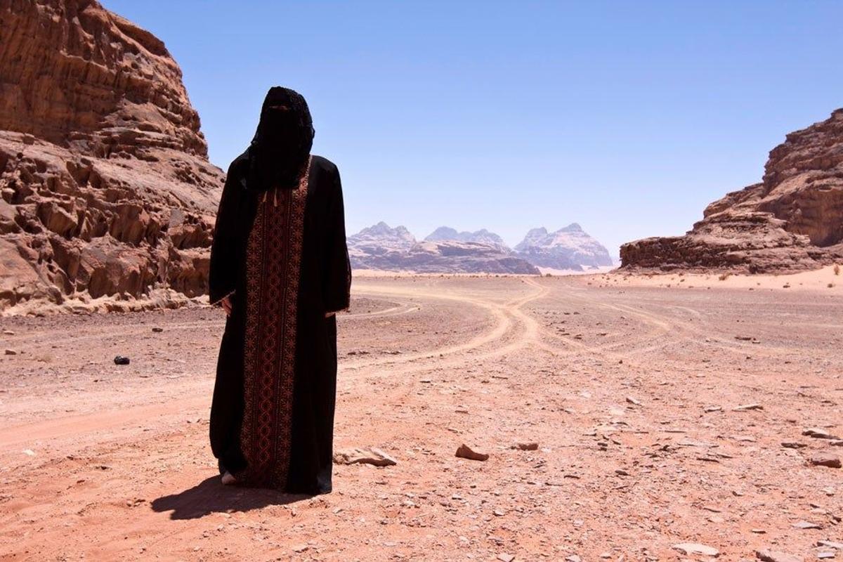 Beduina completamente tapada bajo su burka en el desierto
