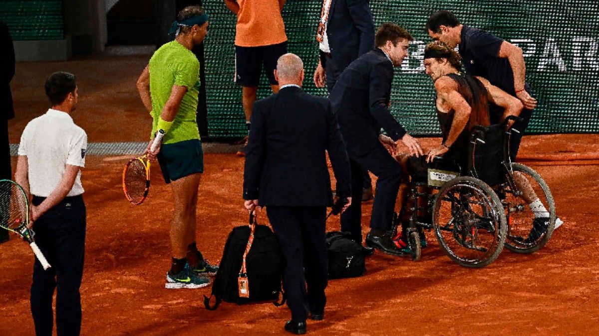 Nadal observa como Zverev abandona la pista central de Roland Garros en silla de ruedas tras su lesión en el tobillo derecho.