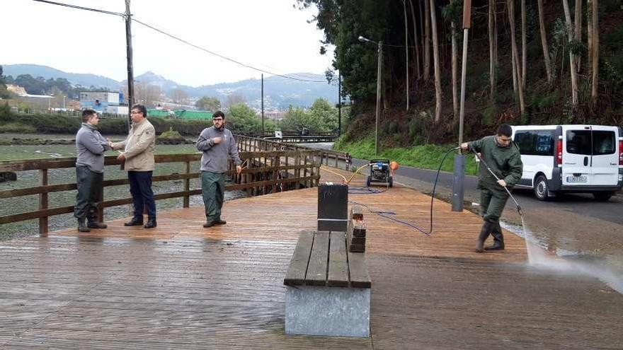 Los operarios realizan labores de limpieza en el paseo de madera de A Portela. // FdV