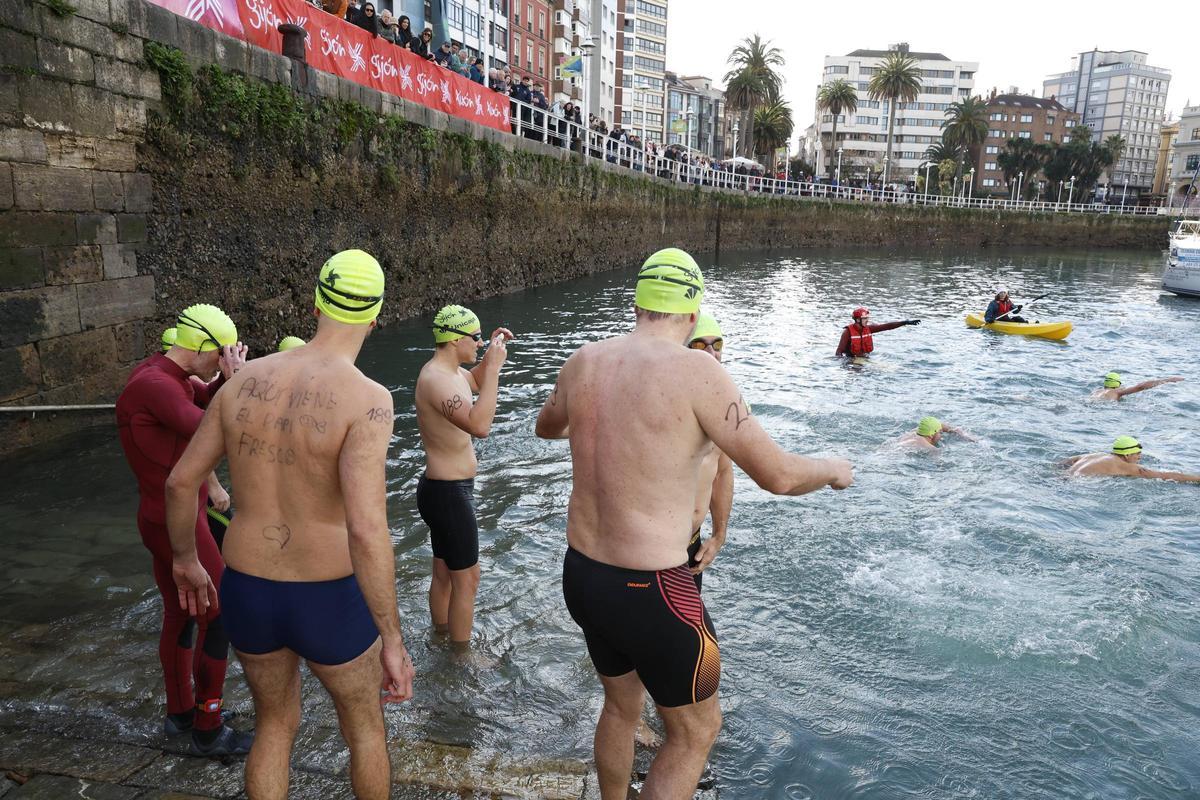 La travesía a nado de Navidad en Gijón congrega un año más a decenas de participantes (en imágenes)