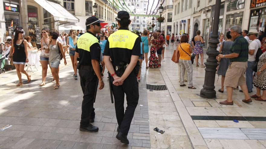 Una pareja de policías locales patrulla en la calle Larios durante la Feria.