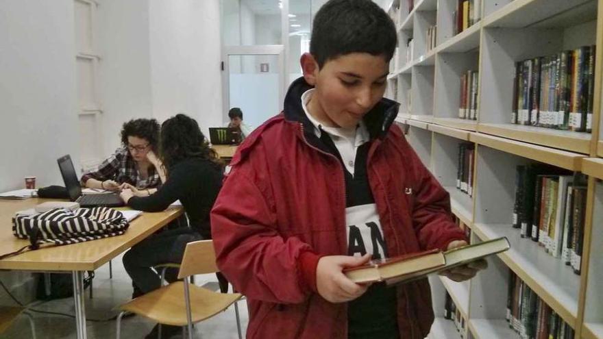 Un niño aprovecha las vacaciones escolares para elegir un libro en la biblioteca.