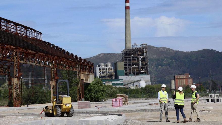 La alcaldesa de Langreo, en el centro, en la explanada de talleres de Conde que acogerá un aparcamiento, con la térmica de Lada al fondo. | ZAI Semeyes