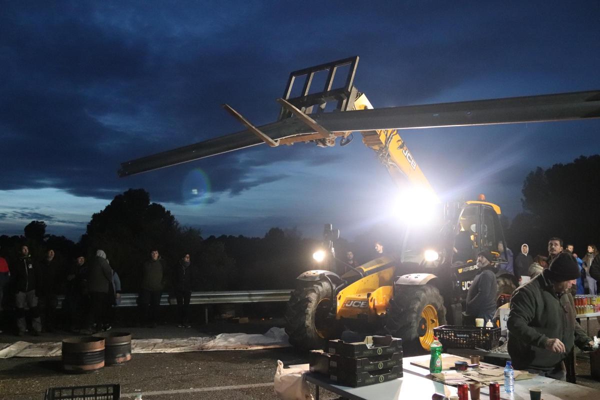 Un tractor porta un guardarail en el tall de l'AP-7 per fer-hi un cobert on passar la nit.