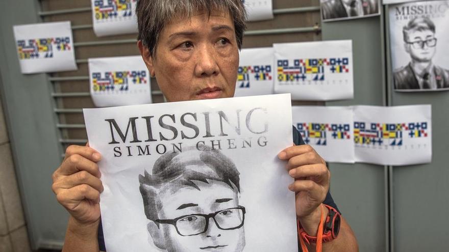 Una activista sostiene una pancarta con una ilustración de Simon Cheng.
