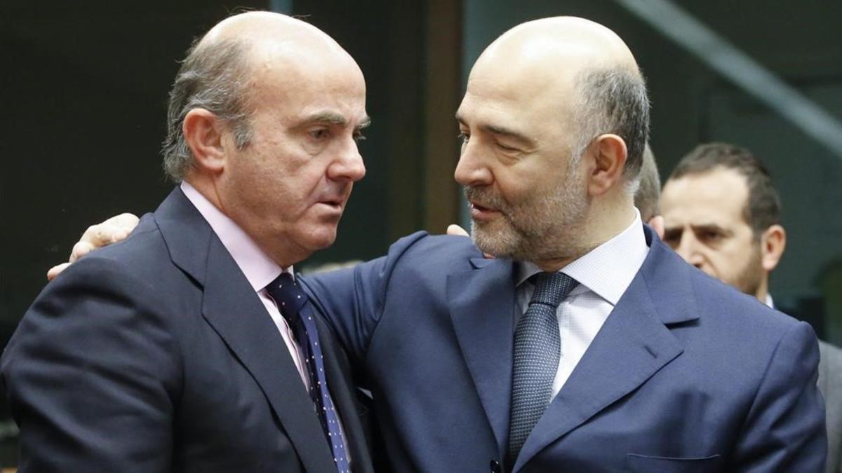 El ministro espanol de Economia, Luis de Guindos, conversa con el comisario europeo de Asuntos Economicos, Pierre Moscovici.