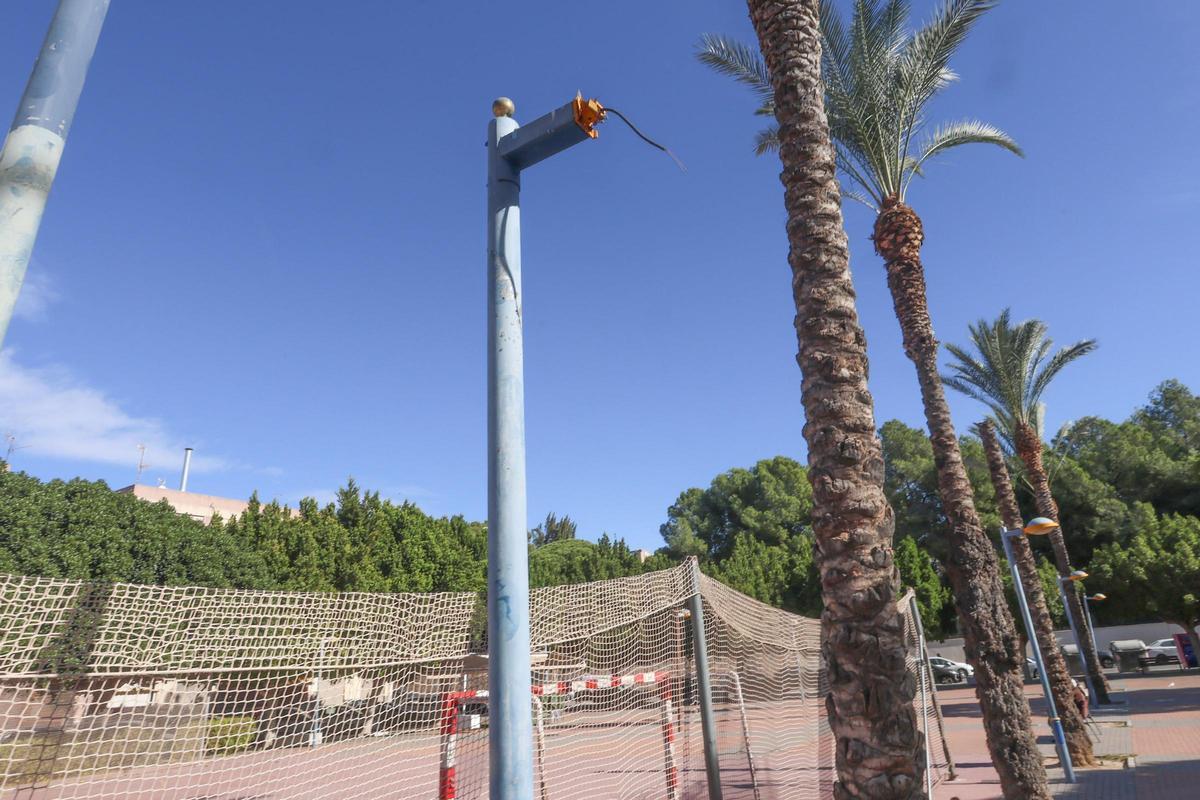 Una farola de la que solo cuelgan los cables junto a la pista de la Ocarasa.