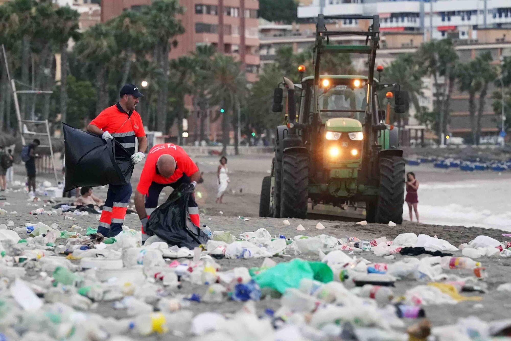 Varios operarios de la empresa de limpieza de Limasam, recogen los residuos de la playa de La Malagueta, tras la Noche de San Juan en Málaga 2025