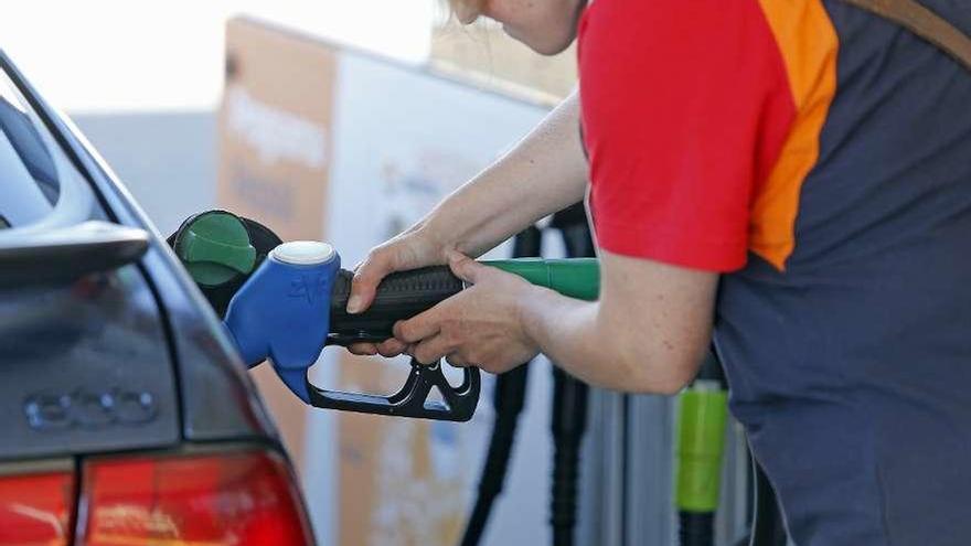 Una empleada de una gasolinera reposta combustible en un vehículo.