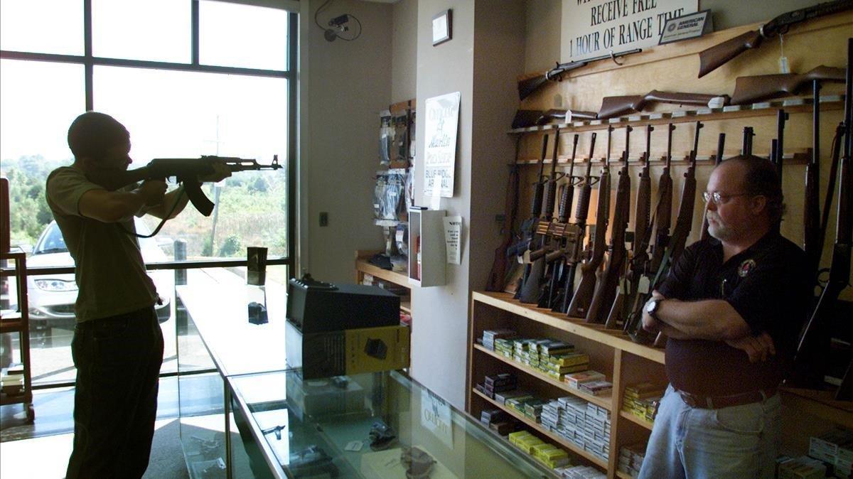 Un hombre prueba un rifle en una tienda de armas. 