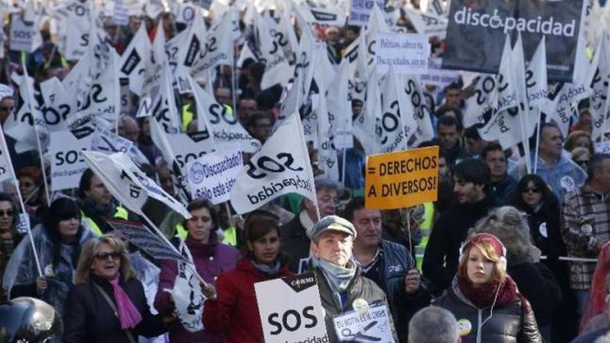 Un grupo de manifestantes, ayer, protesta por los recortes, y cabeza de la manifestación, liderada por una mujer con discapacidad, / reuters / efe