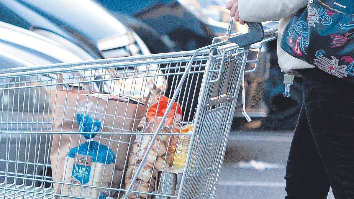 Una persona camina junto a su carro de la compra, en una imagen de archivo