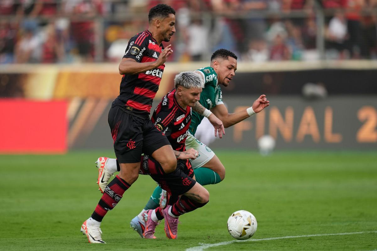 Vitor Roque of Brazil's Palmeiras, right, battles for the ball with Guillermo Varela, center, and Danilo of Brazil's Flamengo during a Copa Libertadores final soccer match in Lima, Peru, Saturday, Nov. 29, 2025. (AP Photo/Martin Mejia)