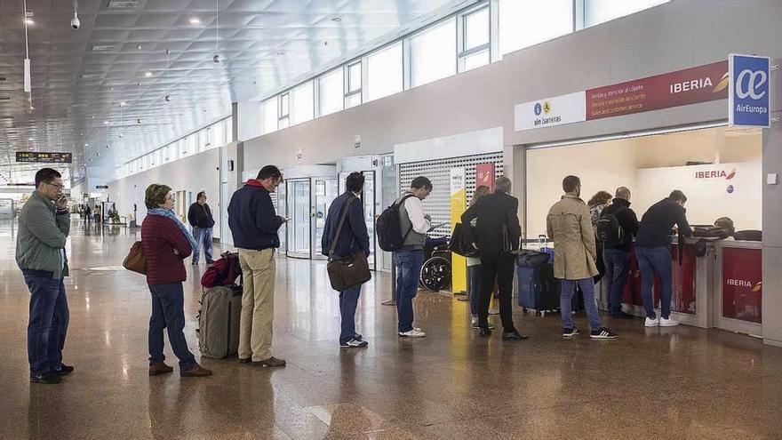 Pasajeros haciendo cola ayer por la mañana ante el mostrador de Iberia en Peinador para presentar reclamaciones. // Cristina Graña