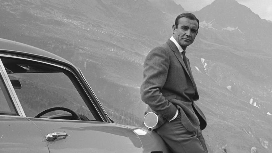 El actor Sean Connery descansando en el parachoques de su Aston Martin DB5 durante el rodaje de James Bond.