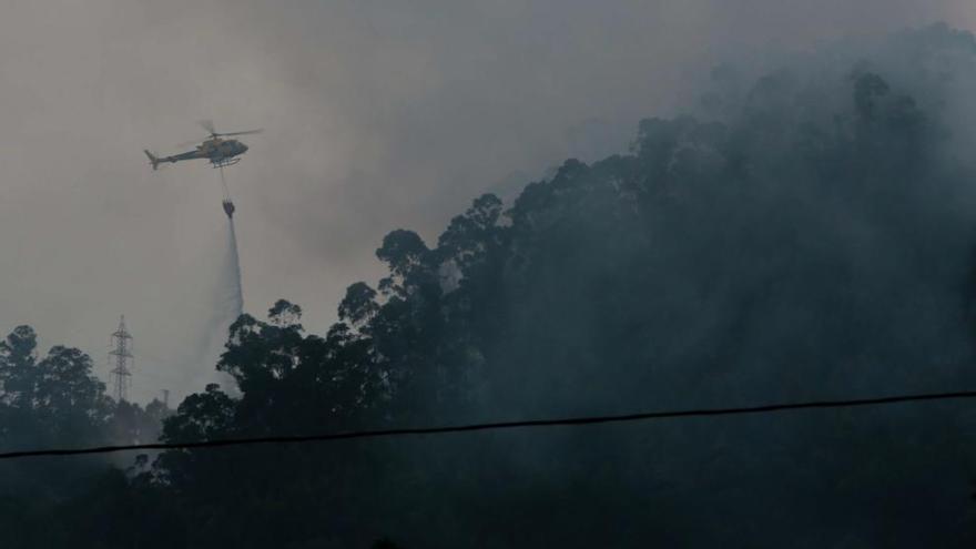 Un helicóptero vacía una bolsa de agua sobre el incendio del Escañorio. | Ricardo Solís