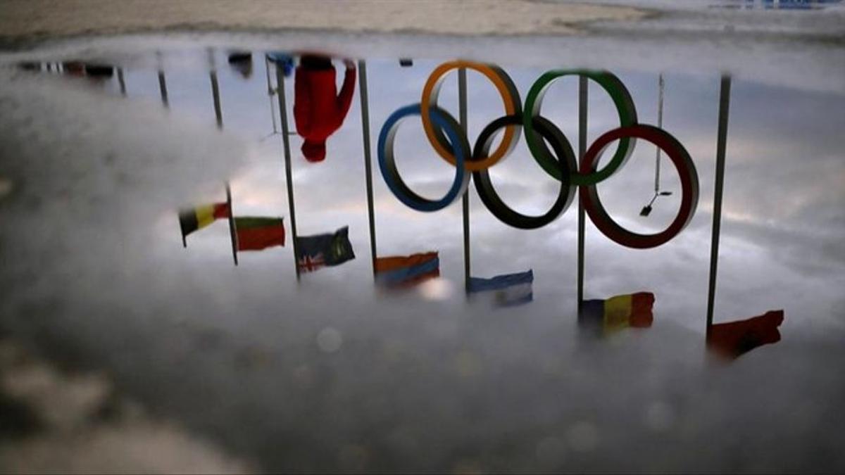Los aros y banderas olímpicos reflejados en el suelo del parque olímpico.