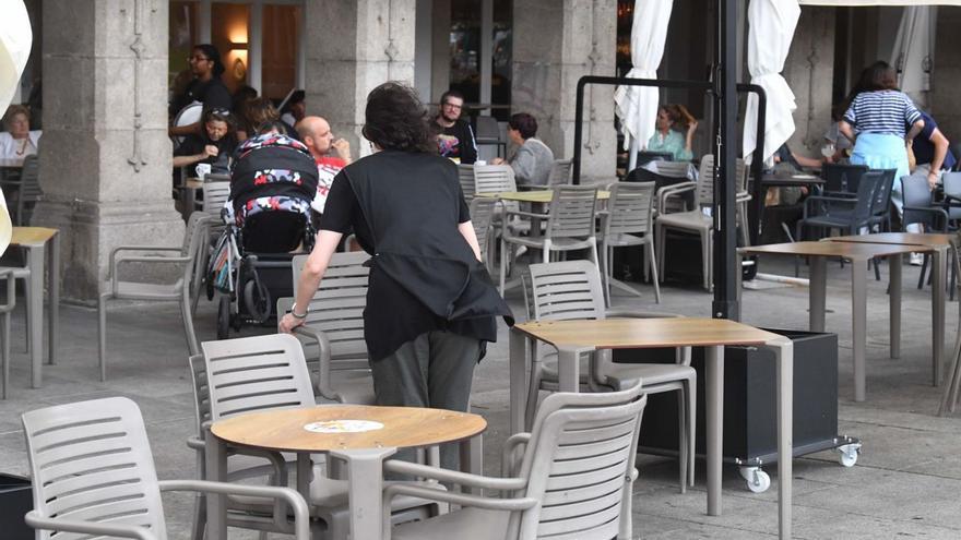 Una camarera coloca las sillas en una terraza de A Coruña. | V. Echave