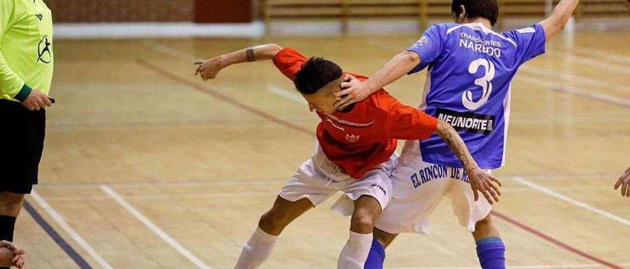 Dos jugadores pugnan por el balón ante la mirada del árbitro.